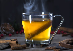 Hot whisky, rum, apple or brandy toddy cocktail drink with cinnamon set on rustic wood